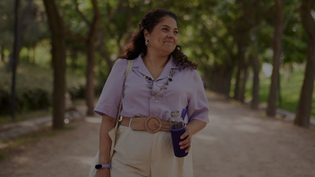 A woman walks in the park while holding a water bottle