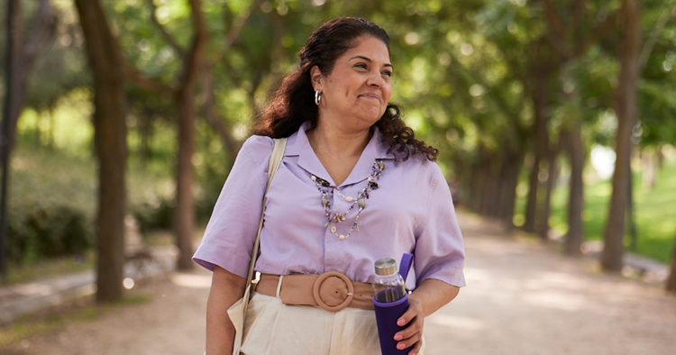 A woman walks in the park while holding a water bottle